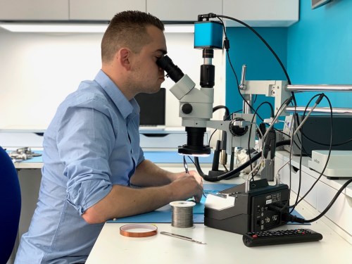Technician performing micro-soldering on a logic board